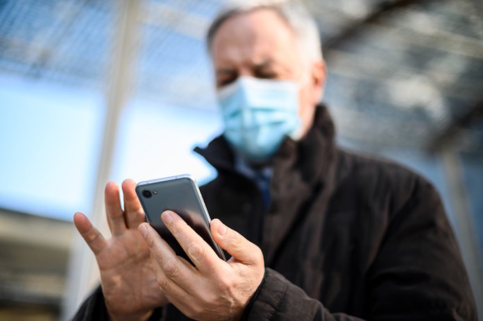 Man with mask on using phone