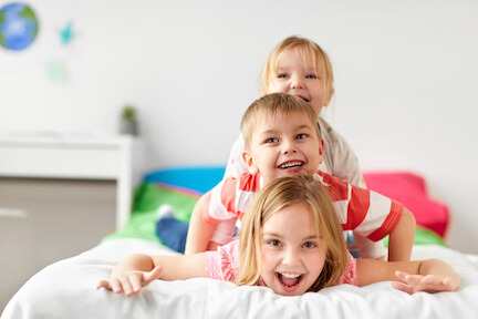 3 children playing on a mattress