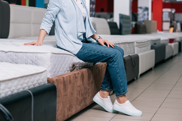 woman sitting on mattress in furniture shop