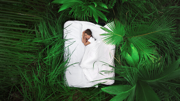 Woman sleeping on a mattress in the jungle.