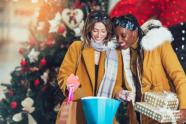 Twoattractivemultiethnicyoungwomenholdingshoppingbagsandsmiling