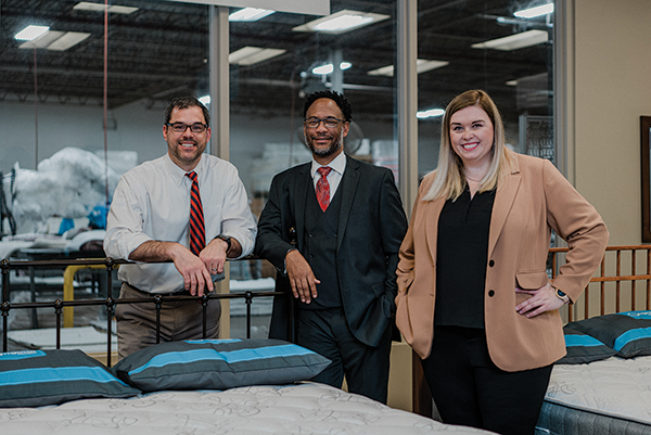  INVOLVED TEAM (From left) Greg Trzcinski, president and CEO of The Original Mattress Factory; David Phillips, a sales and marketing partner; and Kristen Hastings, director of corporate marketing, regularly take turns working showroom floors. 
