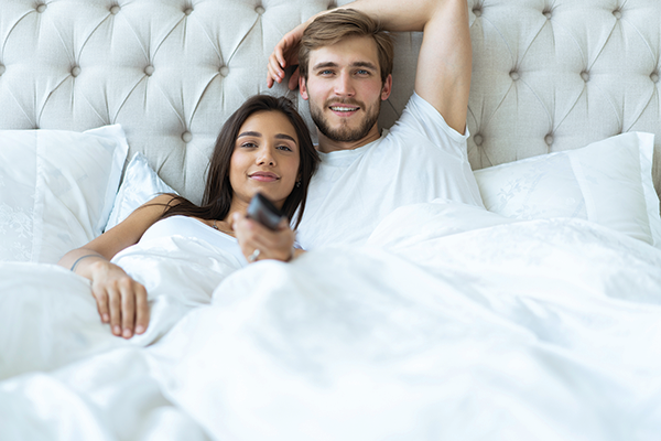 man and woman watching tv in bed