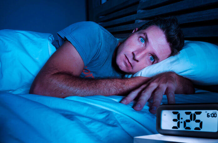 restless worried young attractive man awake at night lying on be