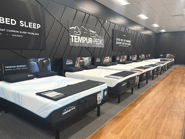 Clear signage inside the showroom directs shoppers to a lineup of Tempur-Pedic mattresses.