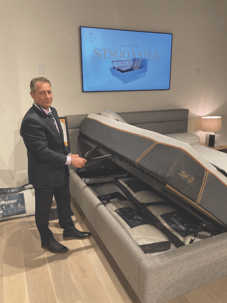 Rising up Symphony Sleep CEO John Schulte demonstrates how the ST800 Platform Storage Bed lifts to provide access to a storage space under the bed.
