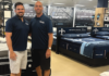 Garret Gustason (left) and Michael Gustason pose in front of the bedding section of Furniture Gallery by Mattress Mike.