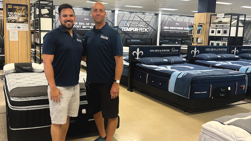 DREAM TEAM Garret Gustason (left) and Michael Gustason pose in front of the bedding section of Furniture Gallery by Mattress Mike.