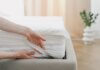 For Value-Focused Shoppers, Small Sleep Add-Ons Can Drive Bigger Sales Person fitting a mattress protector onto a bed