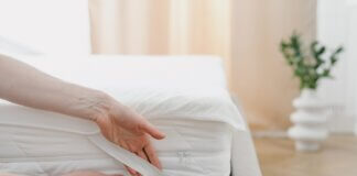Person fitting a mattress protector onto a bed